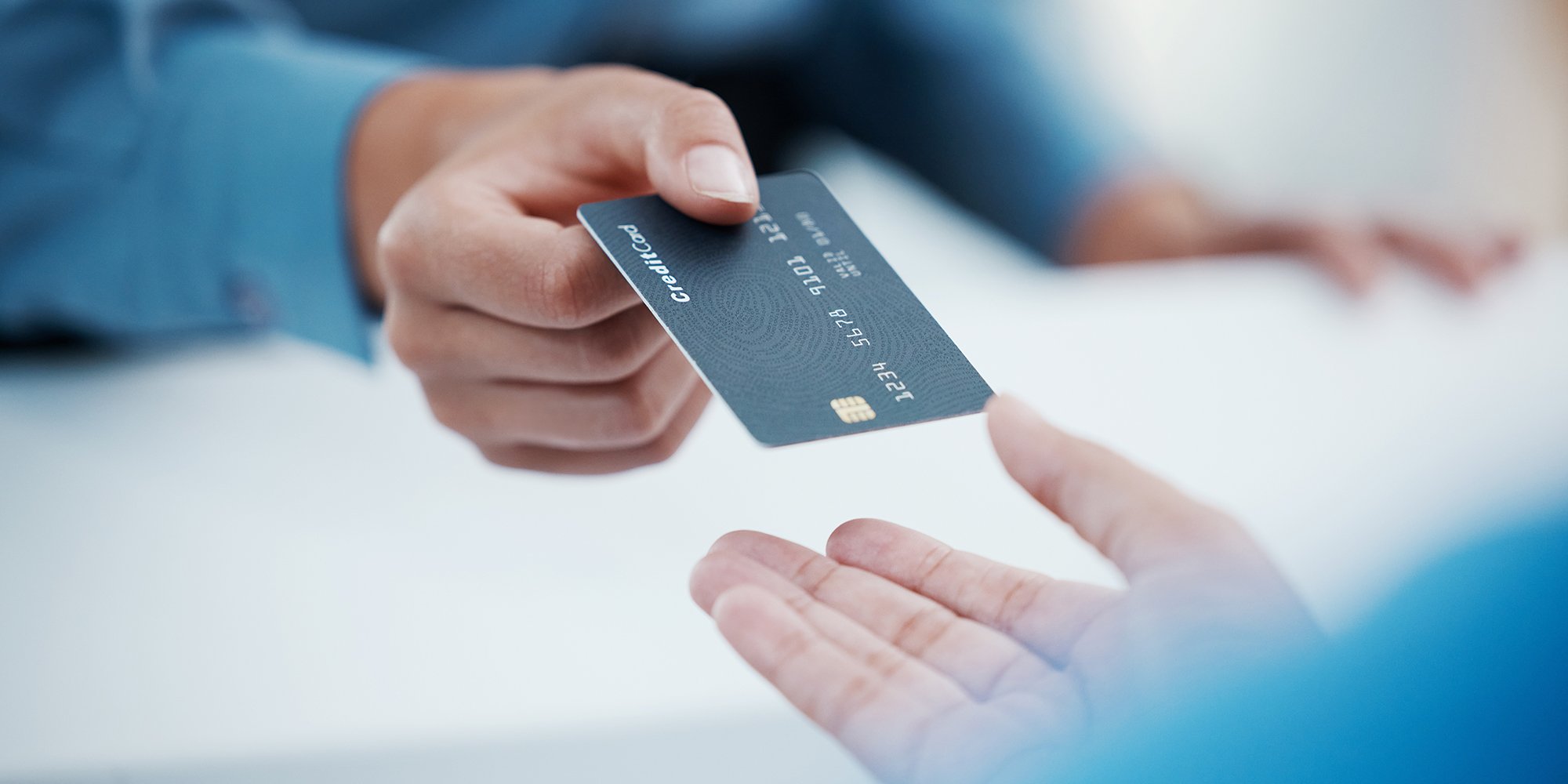 A closeup of a person handing a credit card to another person.