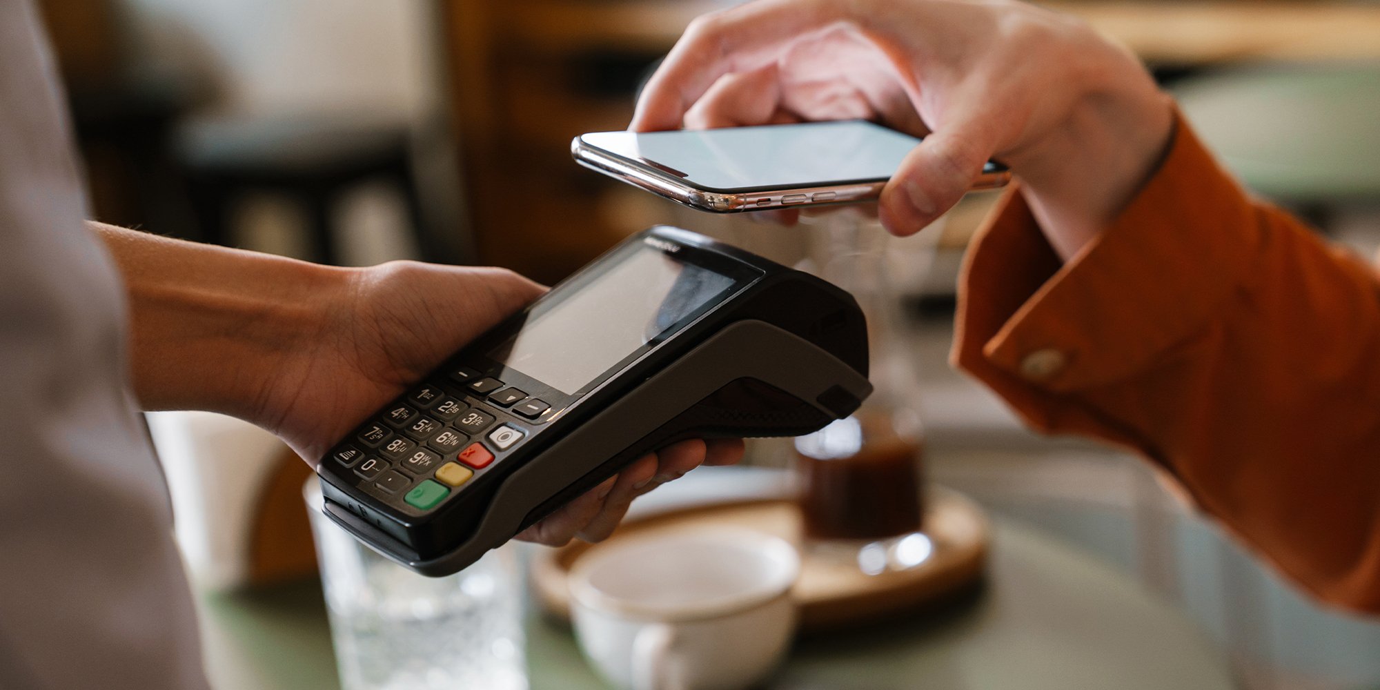 Close up of a person paying with mobile phone using contactless terminal.