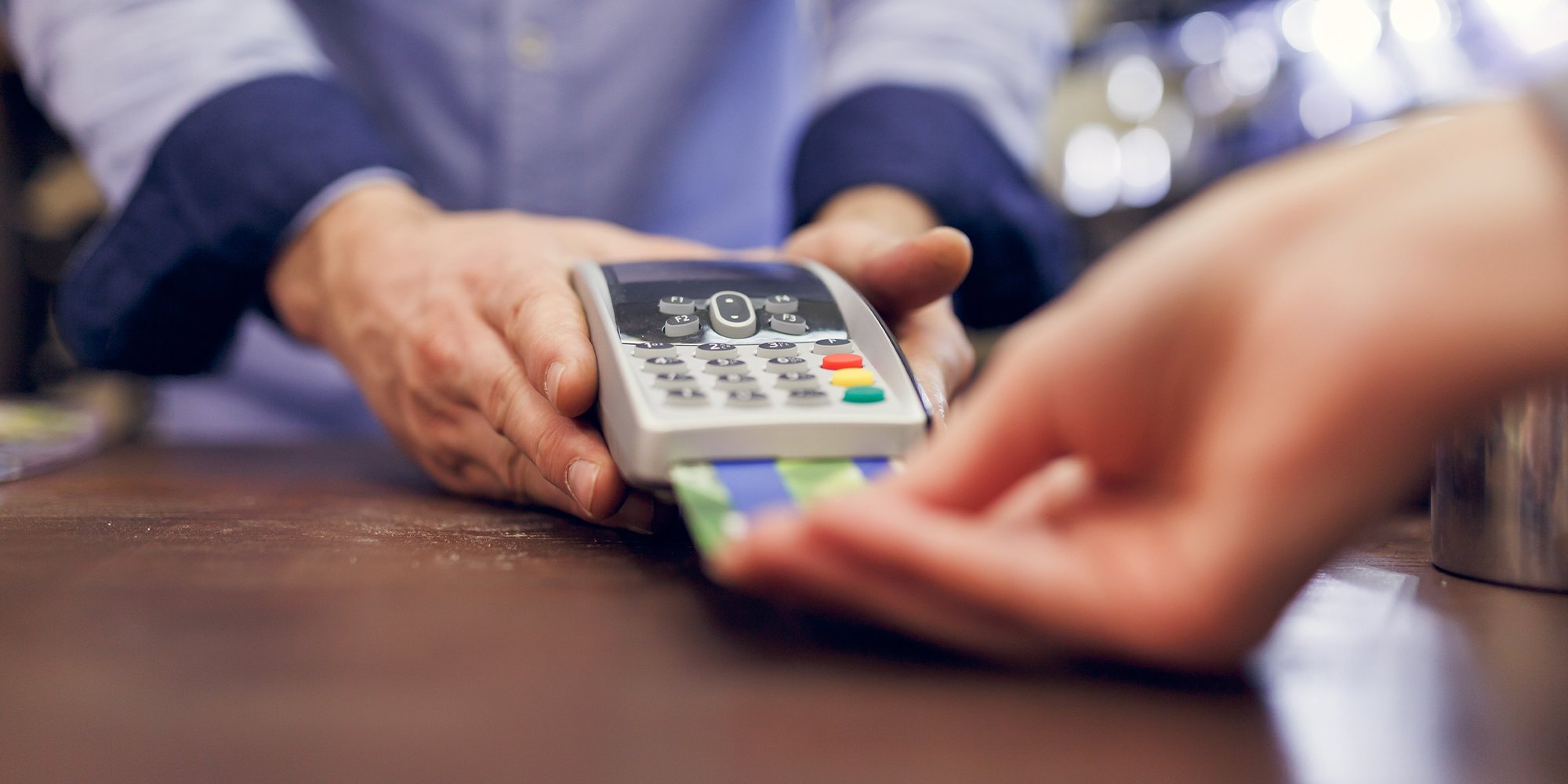 Image of male seller with terminal in hand and buyer with bank card.