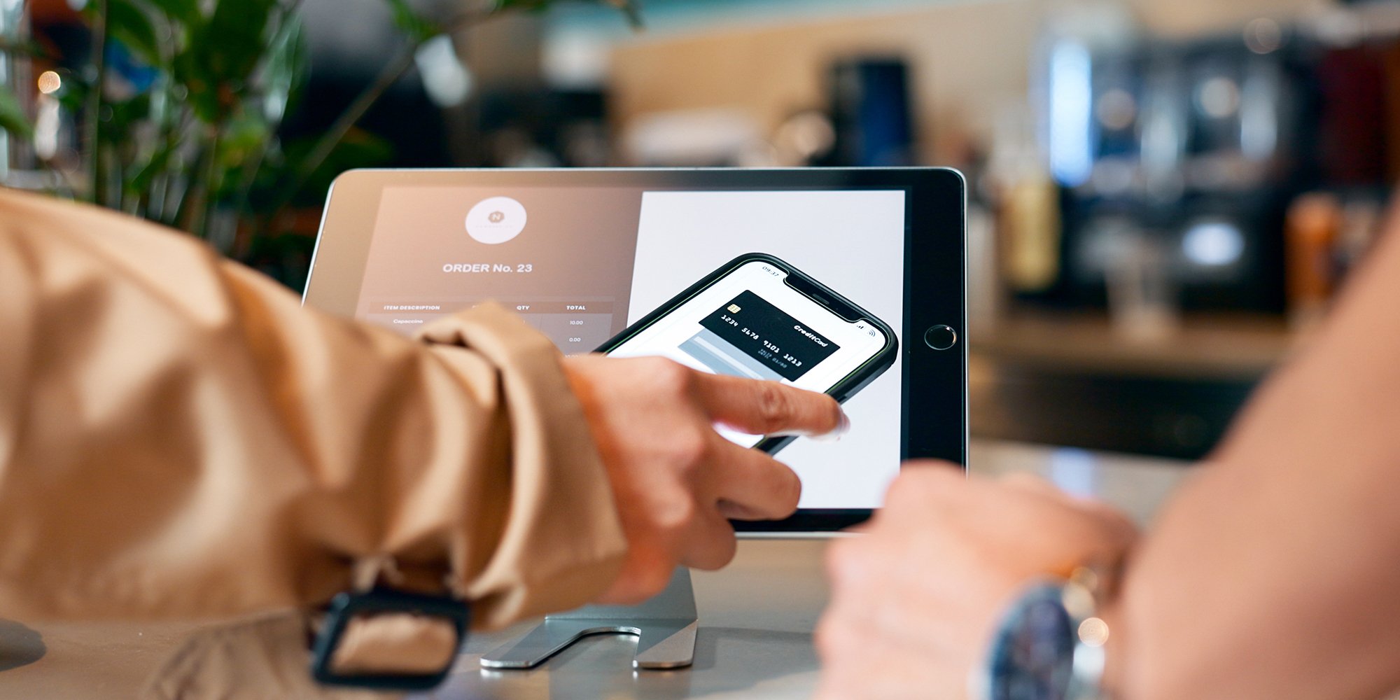 Close up of a person using their smartphone to pay their bill on a tablet.